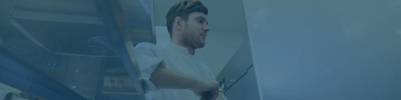 Restaurant chef looking into refrigerator as part of a refrigeration maintenance checklist